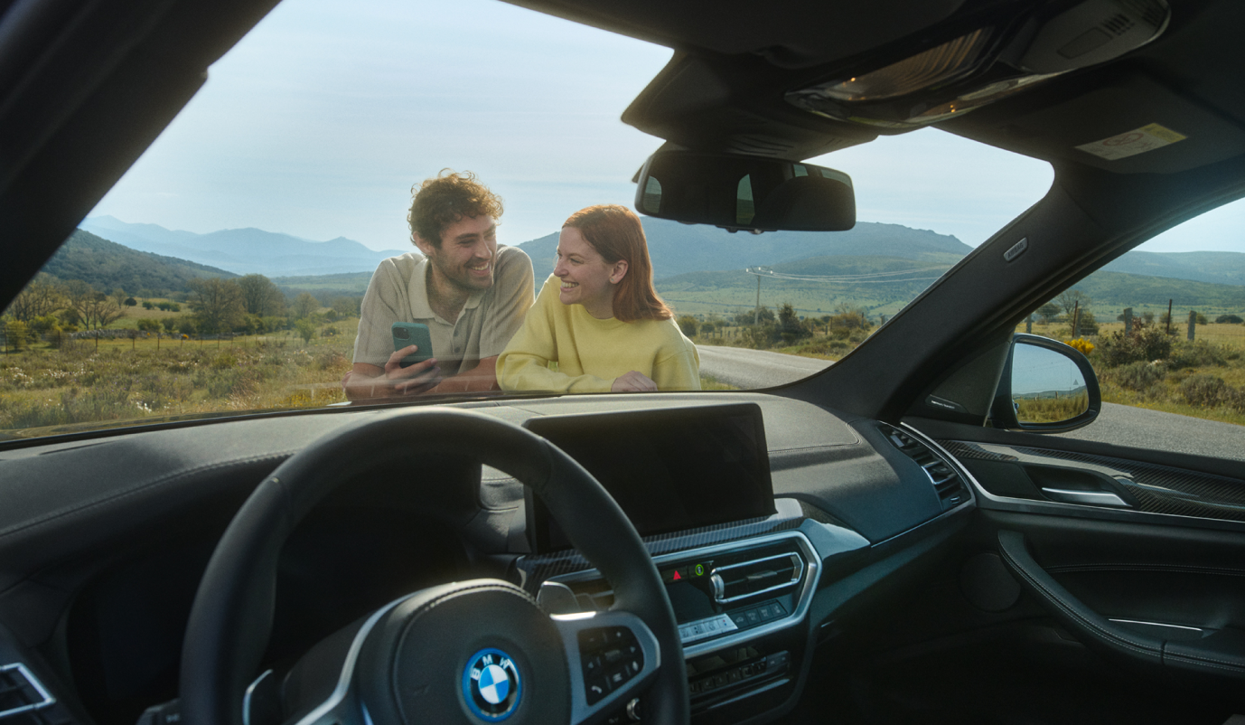 une femme et un homme qui sourient devant une voiture bmw